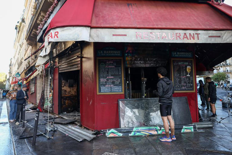 People inspect the damaged restaurant La Barrique, the day after clashes during a national day of demonstrations against the cost of living and rising fuel prices, near the Place de la Republique in Paris, France, October 18, 2026. REUTERS/Abdul Saboor