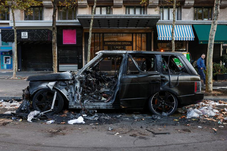 A burnt car sits on a street a day after clashes during a national day of demonstrations against the cost of living and rising fuel prices, in Paris, France, October 18, 2026. REUTERS/Benoit Tessier