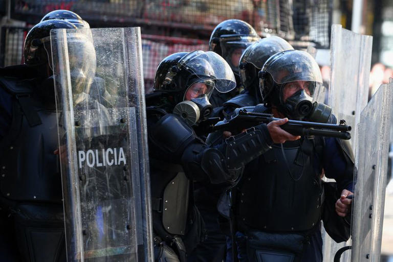 A police officer in riot gear points a gun, during an anti-government protest by students in Tirana, Albania, October 18, 2026. REUTERS/Florion Goga