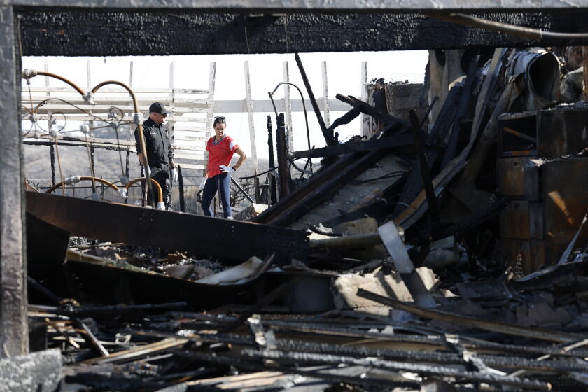 Southern California fires ease as Santa Ana winds die down but rain could bring new risks