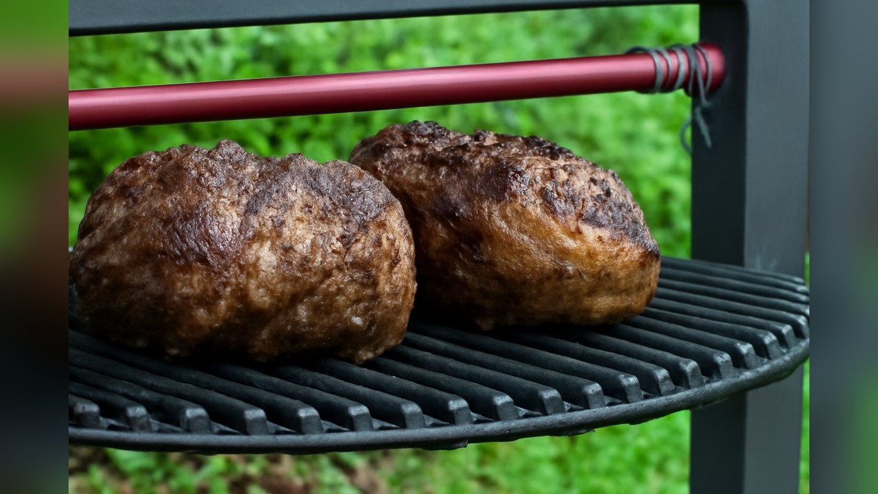 A cook grills and serves large rib steaks