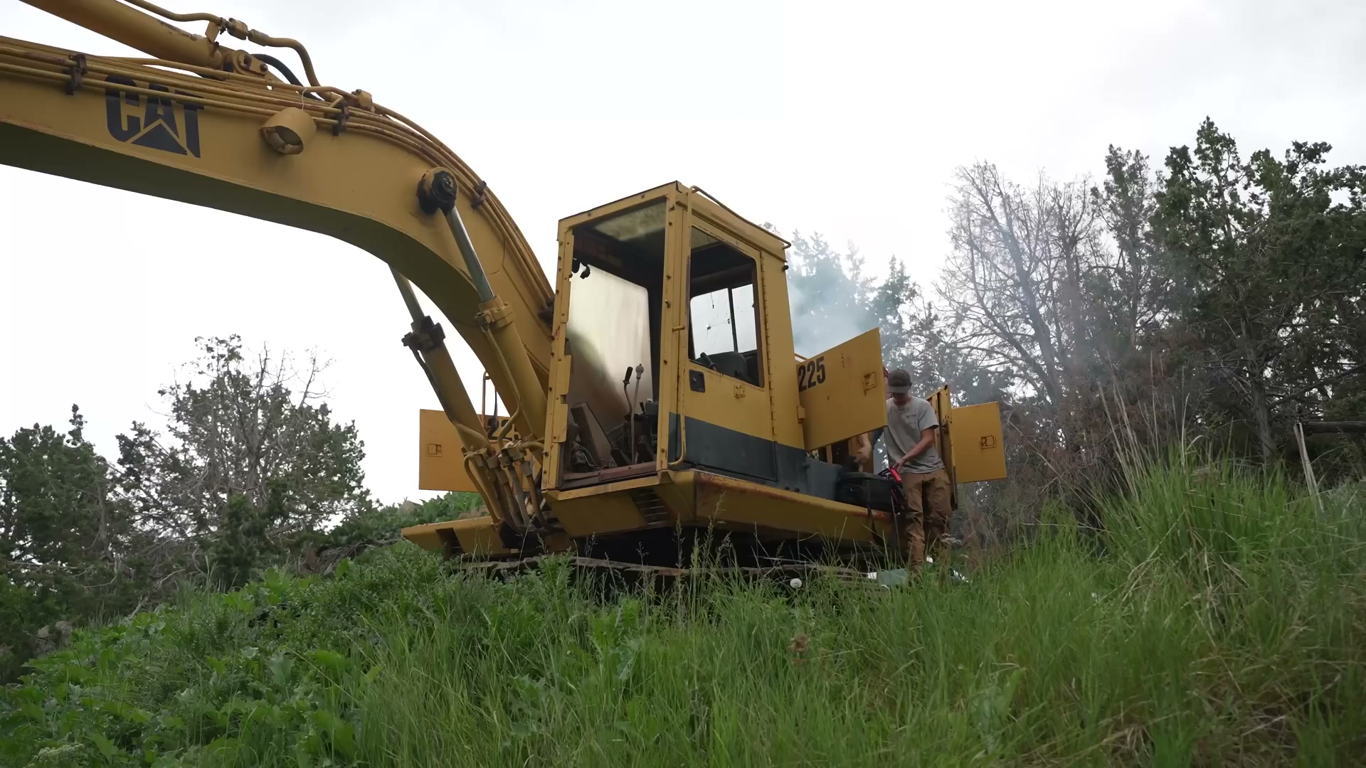 A crew checks oil and fuel to restart an abandoned CAT 225 excavator