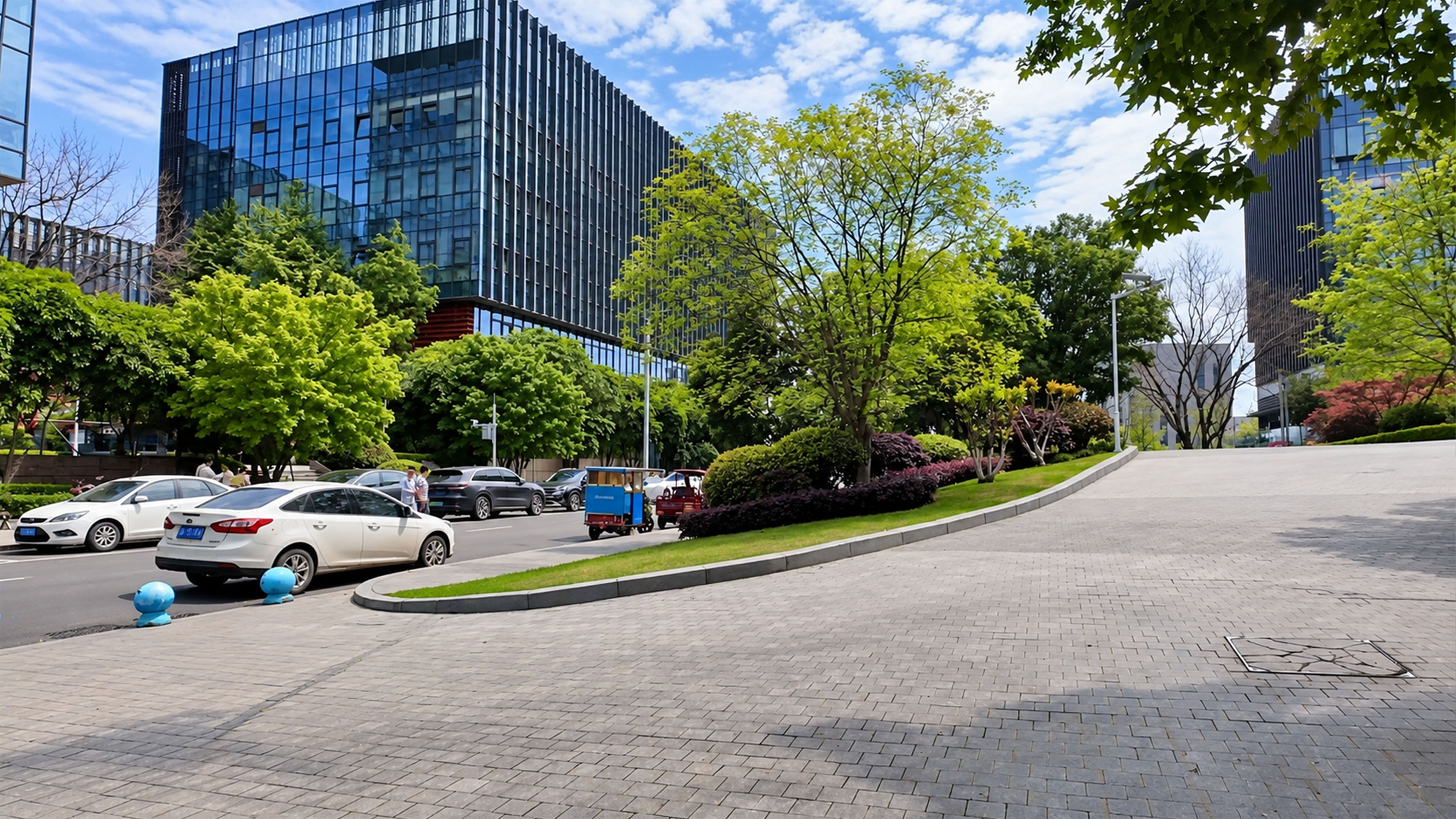 Glass office buildings rise behind this green urban street