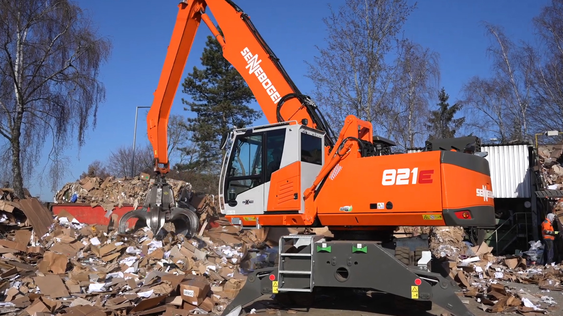 Heavy duty material handler sorting large piles of cardboard waste