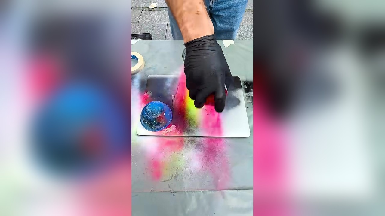 A street artist spray paints a stranger's MacBook