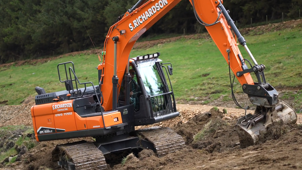 Crawler excavator digging and moving heavy soil on a hillside
