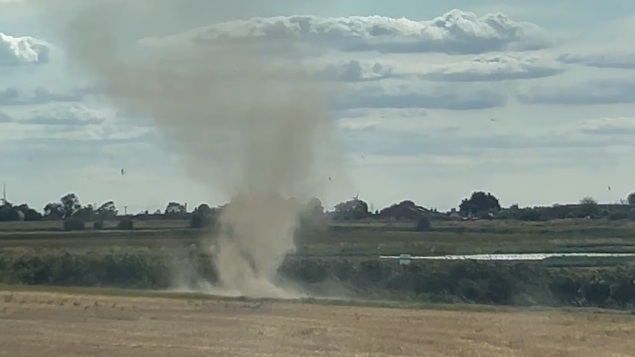 Whirling dust devil twirls wildly beside the road