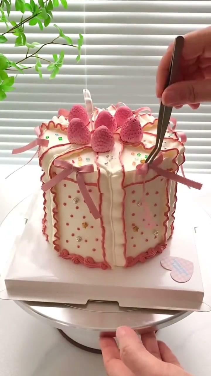 Polka dot gift box cake bursts with pink strawberries and bows