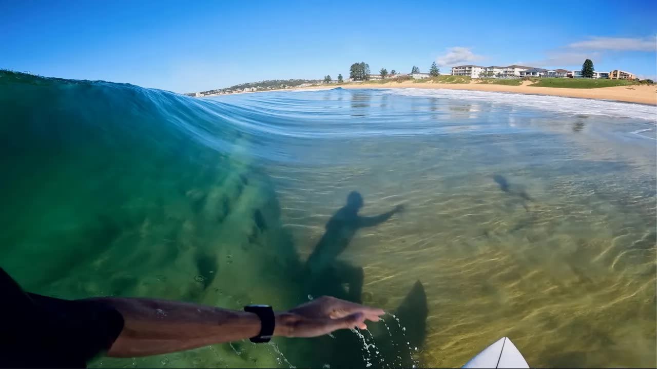 Surfer rides a glassy wave in clear water and spots the bottom