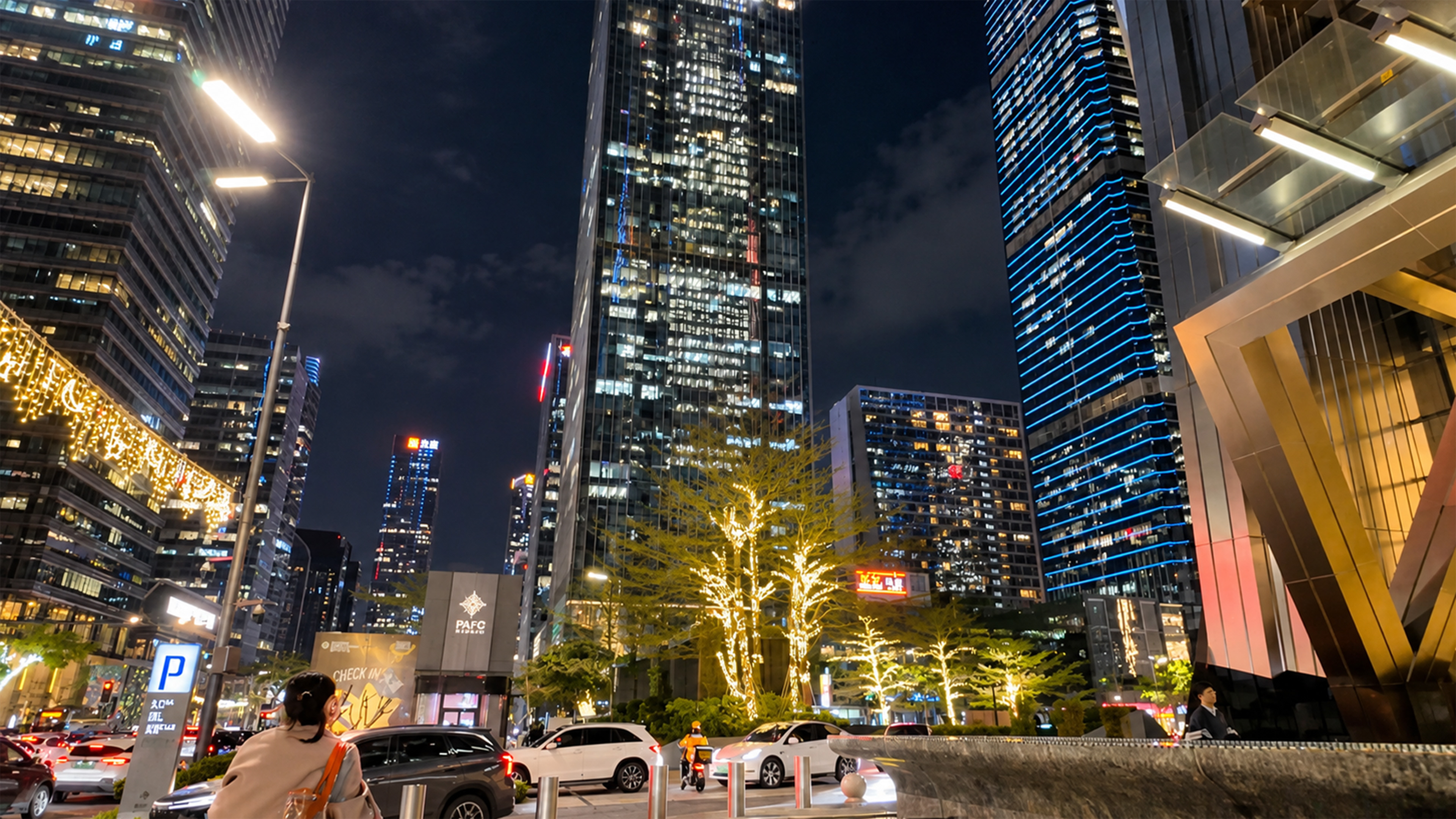 A towering glass skyscraper rises above Shenzhen's glowing trees