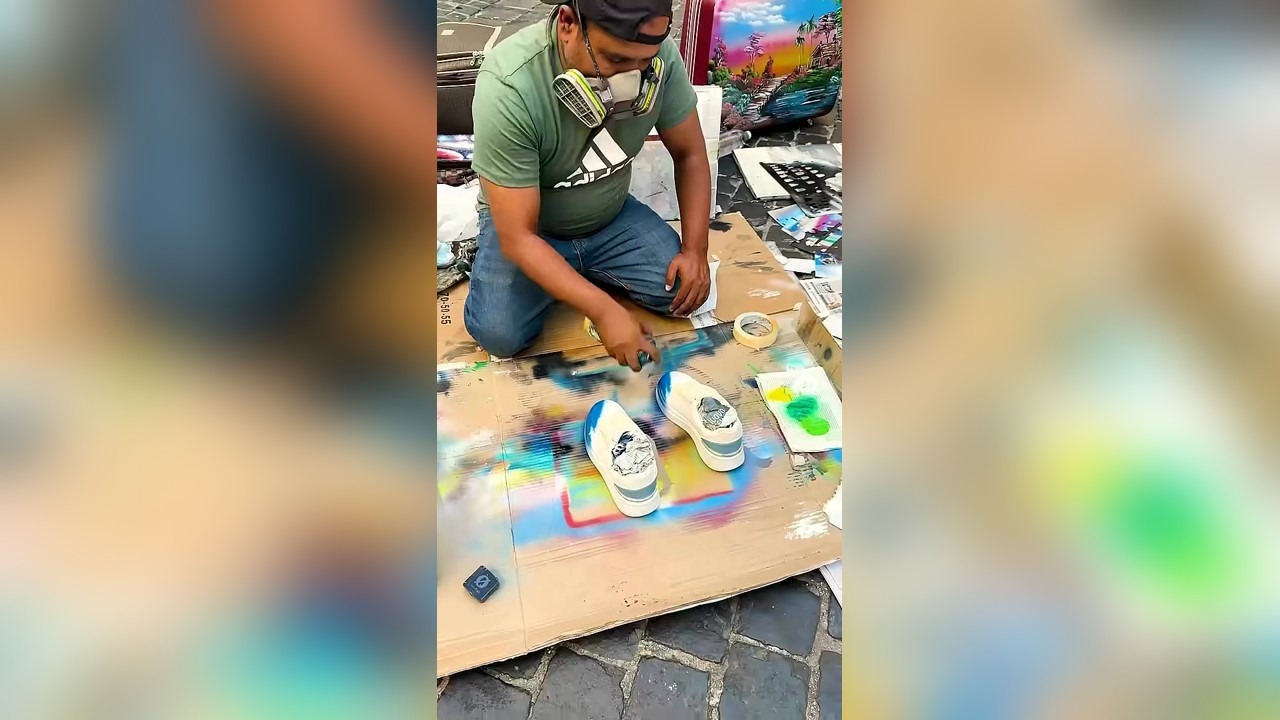 A painter uses a flame while spray painting customer's sneakers