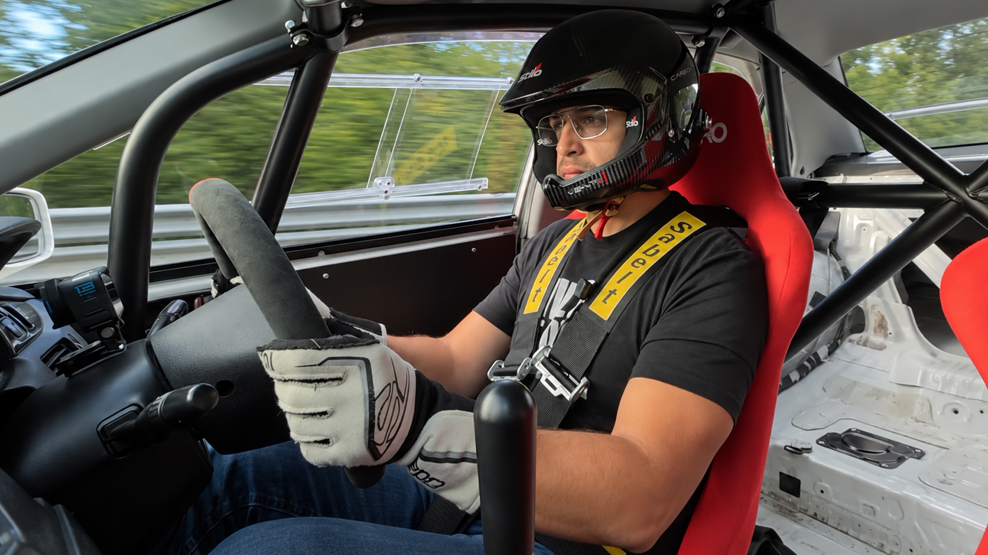 Helmeted driver pushes a full-cage track car