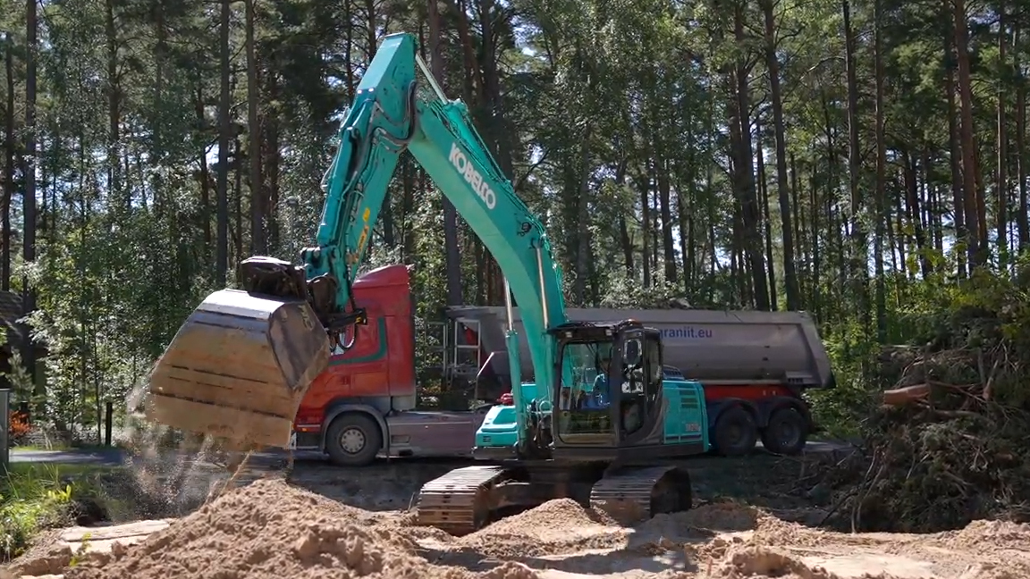 Crawler excavator loading and dumping sand at a forest construction site