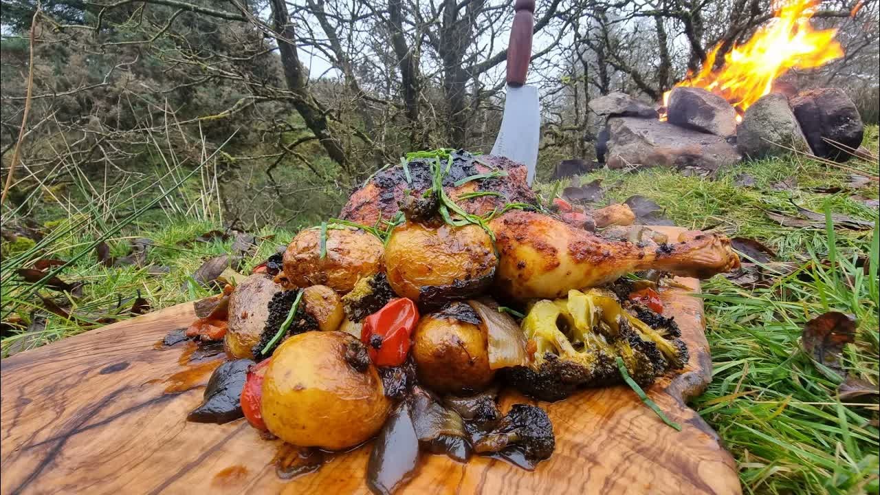 Crispy whole chicken cooks outdoors with potatoes and vegetables