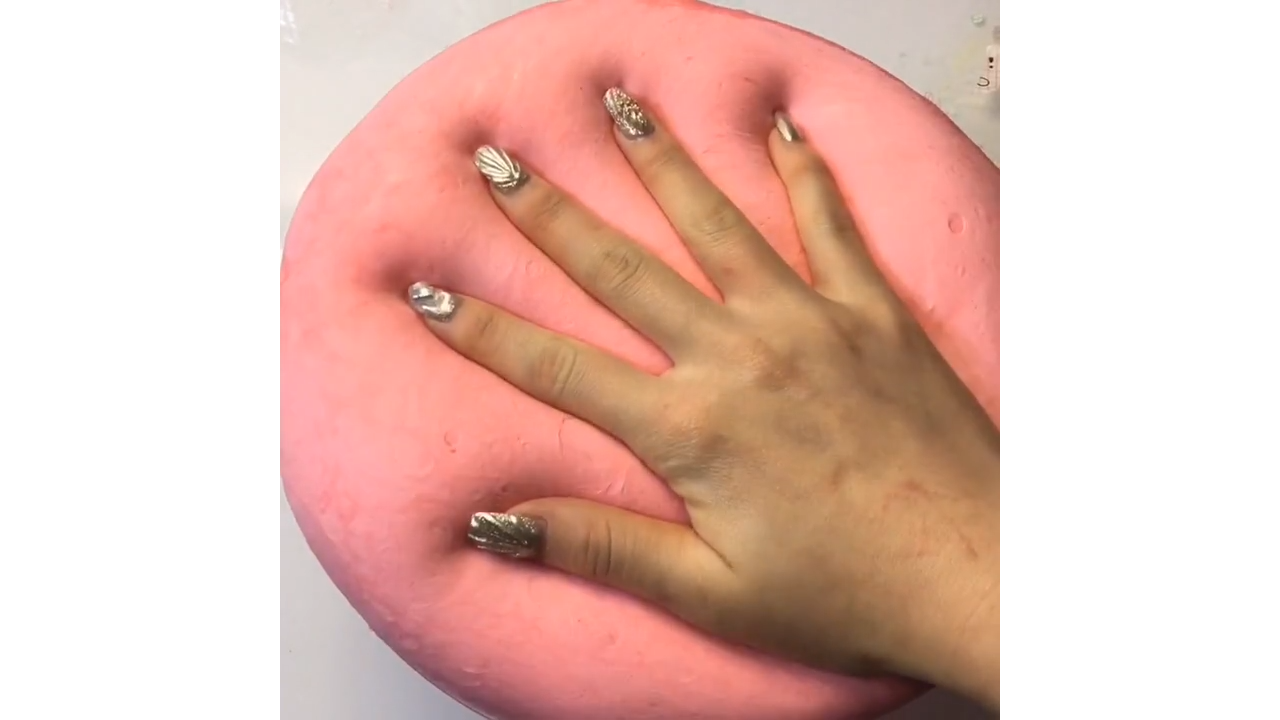 Pressing soft coral pink slime creating satisfying hand imprints