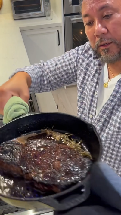 Cooking steak with potatoes, butter, and bacon