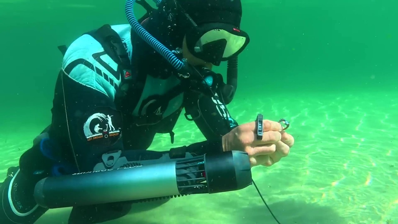 A diver pulls lost jewelry from sand underwater