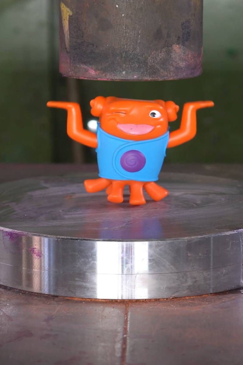 Cartoon toy crushed by a hydraulic press