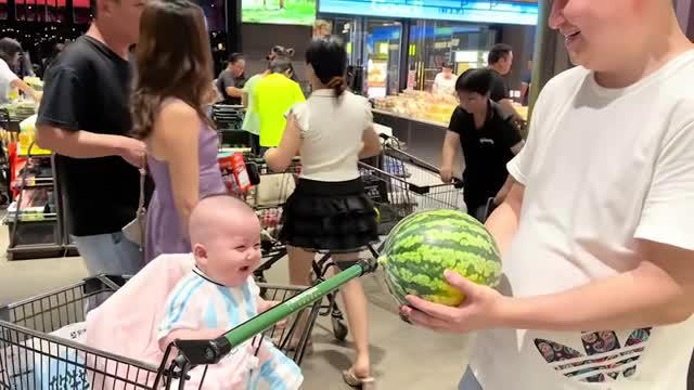 Adorable toddler giggles as father tosses watermelon in front of him