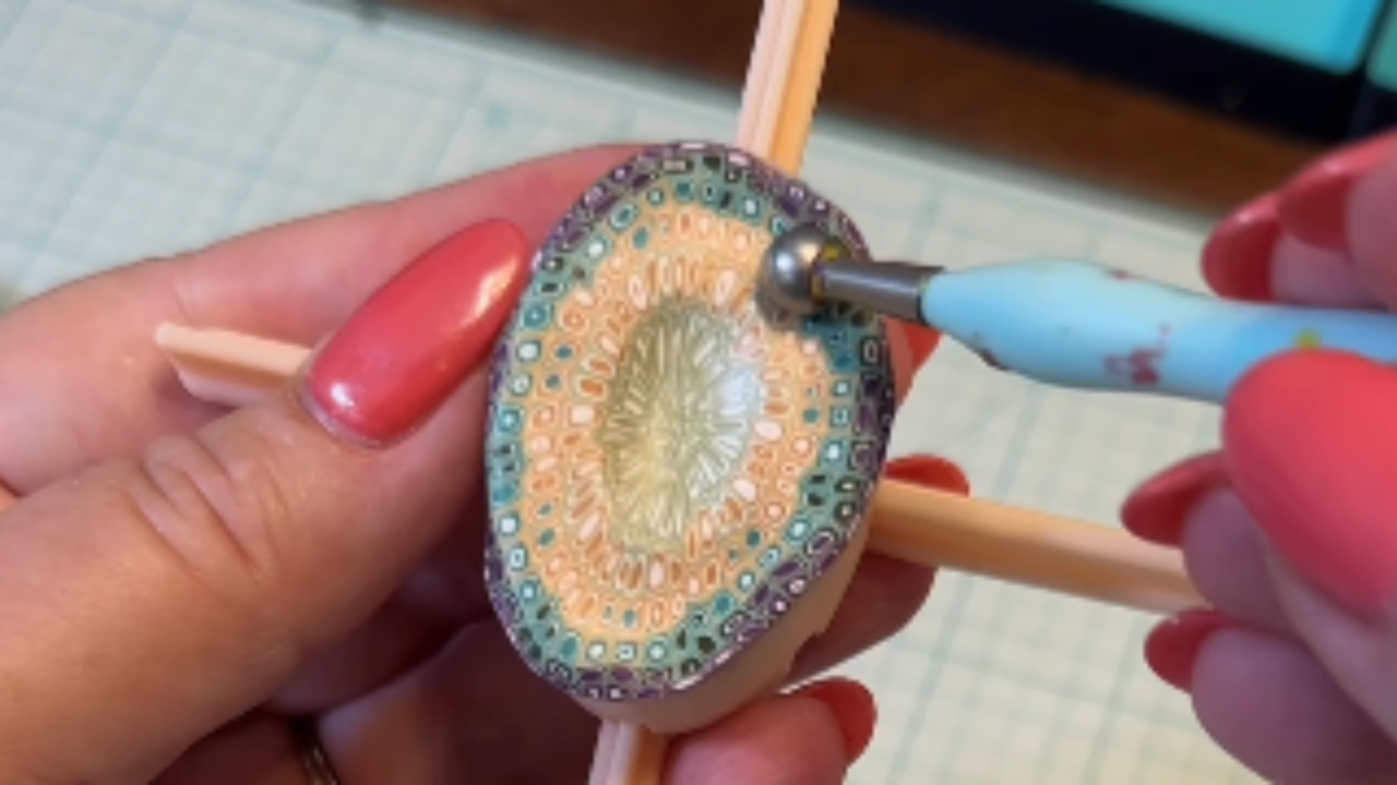 Polymer clay artisan shapes clay into patterned earrings