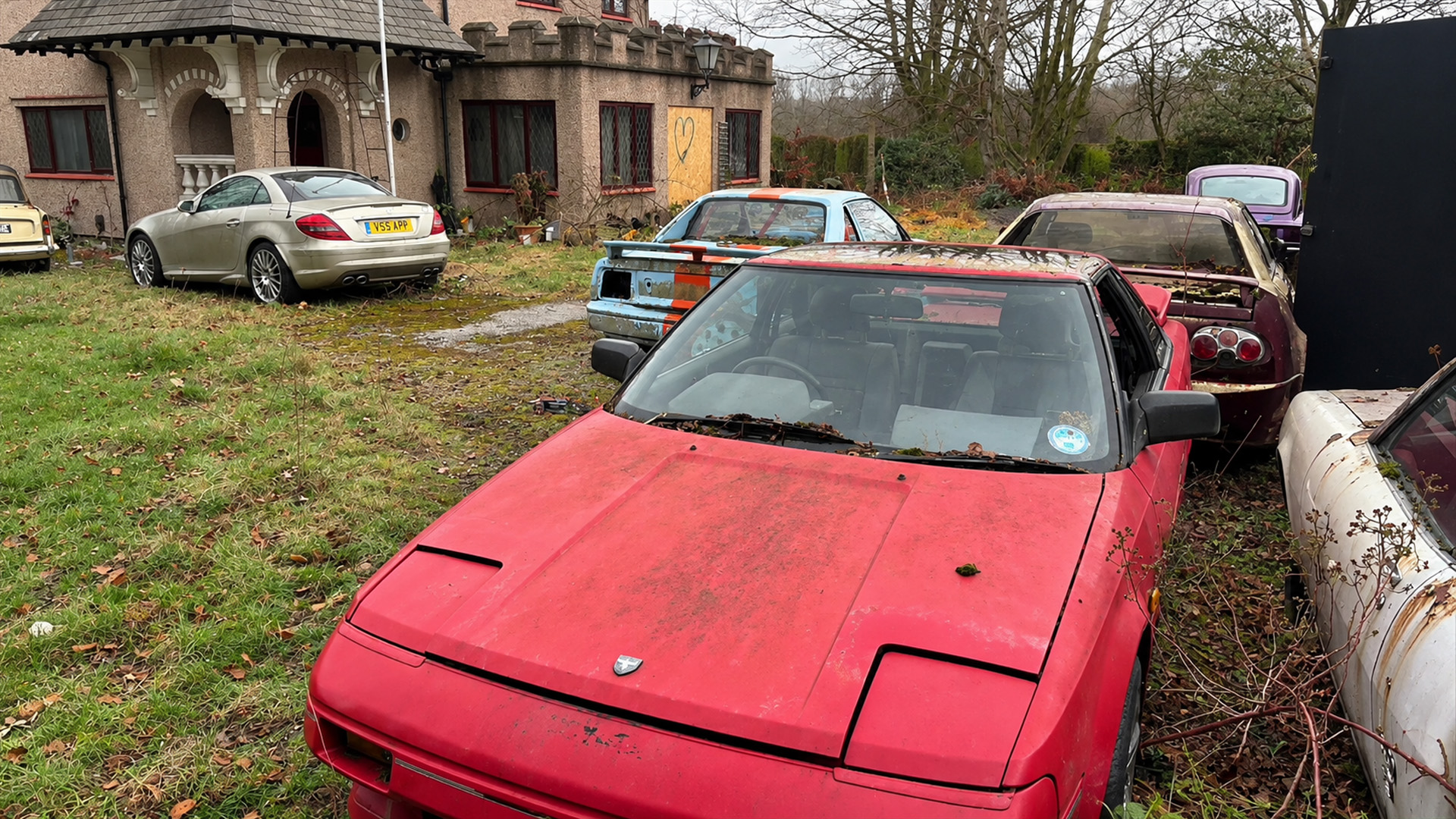 Rare sports cars and a Mercedes remain outside this forgotten mansion