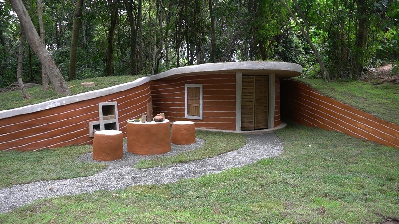 Finished earth-sheltered forest house with a grass roof