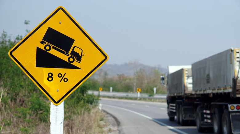 What does the percentage under a semi-truck symbol on a road sign mean?