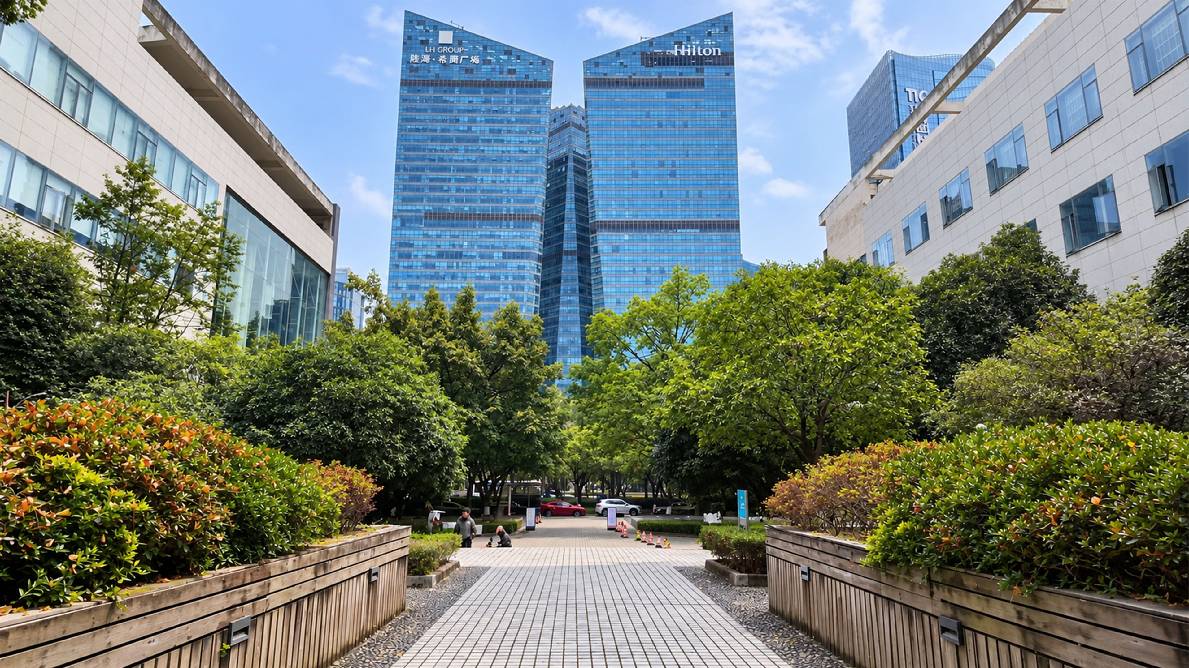 This green walkway in Shenzhen leads toward twin glass towers