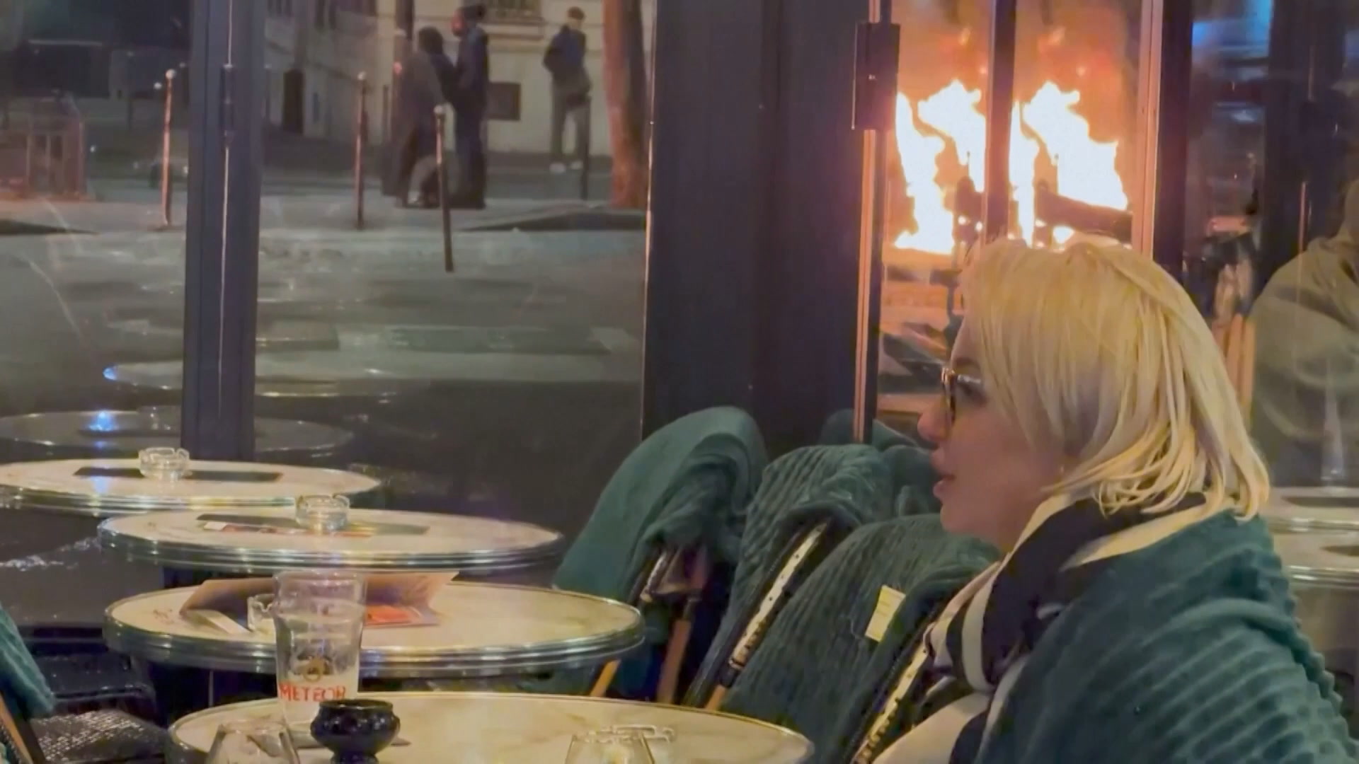 Unfazed couple enjoy drinks as violent riots rage nearby in Paris