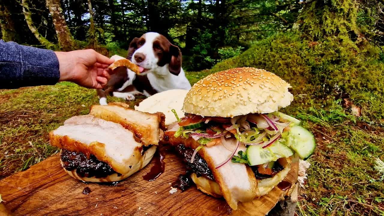 Crispy pork belly burger with caramelized onions cooked over an open fire