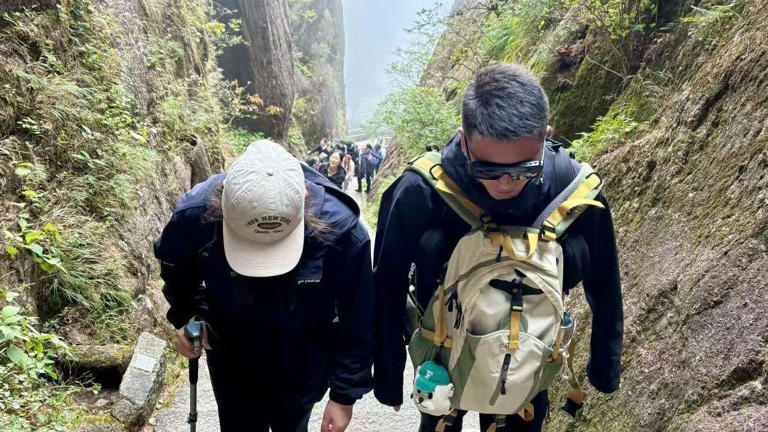 El guía de montaña Wang Zhoutao acompaña a un cliente por las empinadas escaleras del monte Huangshan.