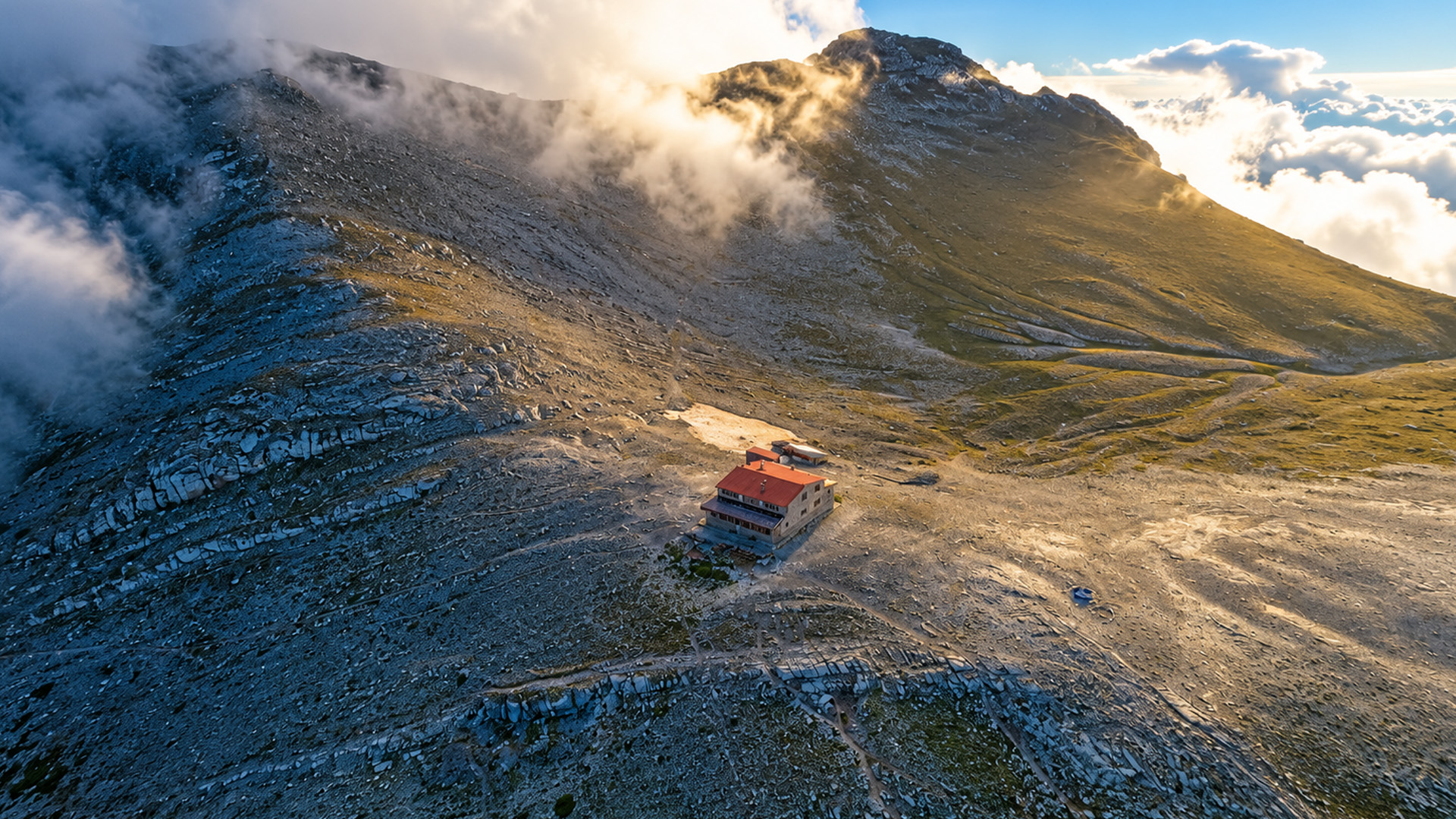 A small red-roofed building beneath Mount Olympus