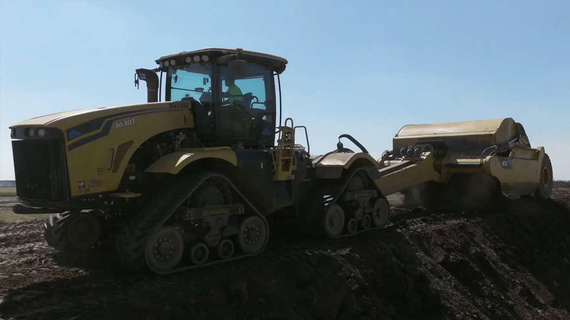 Heavy tracked tractor pulling a large earthmoving scraper