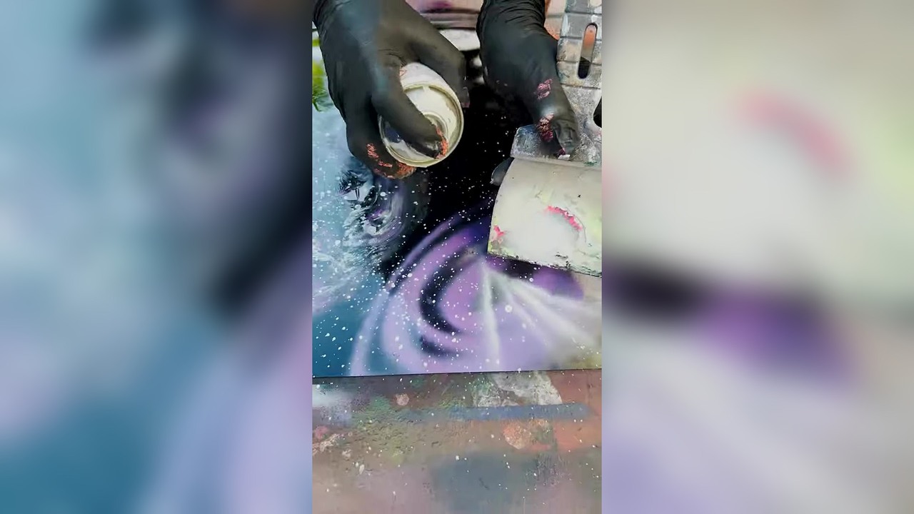 Street artist spray paints a blank canvas