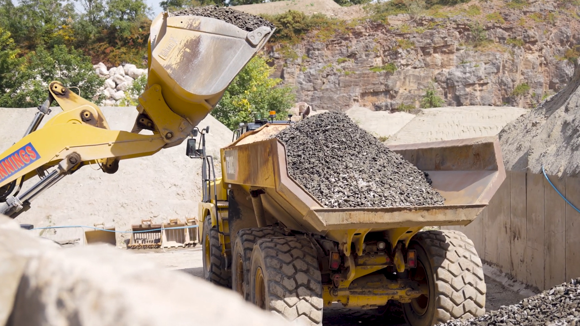 Large wheel loader loading crushed rocks into an articulated dump truck