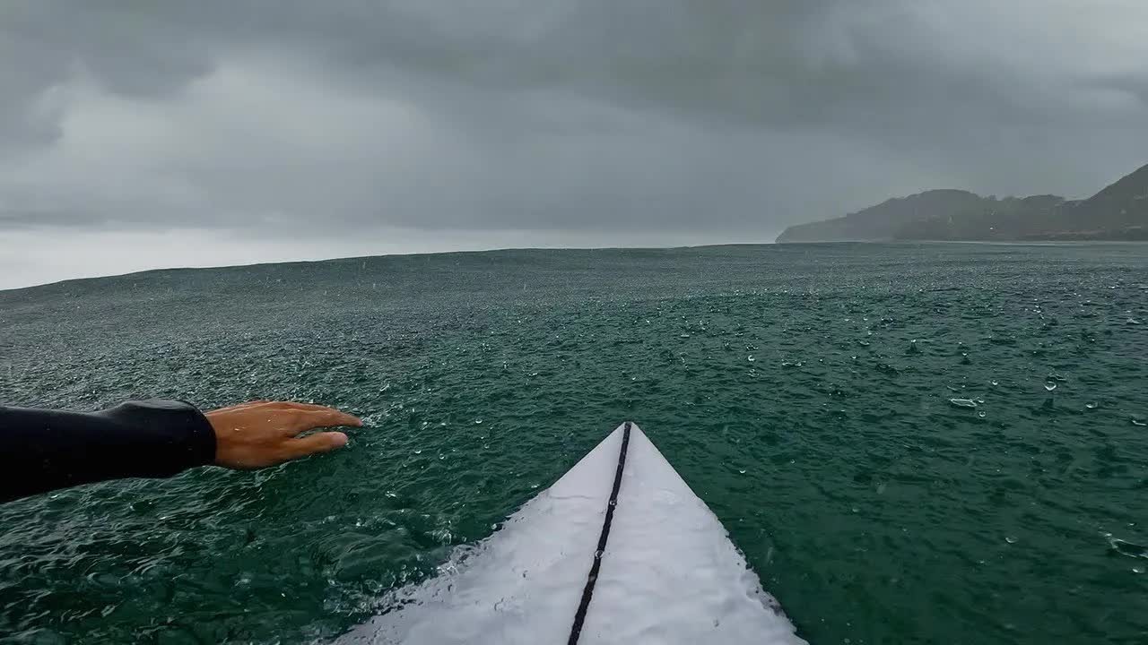 A surfer finds smoother waves during a rainy session