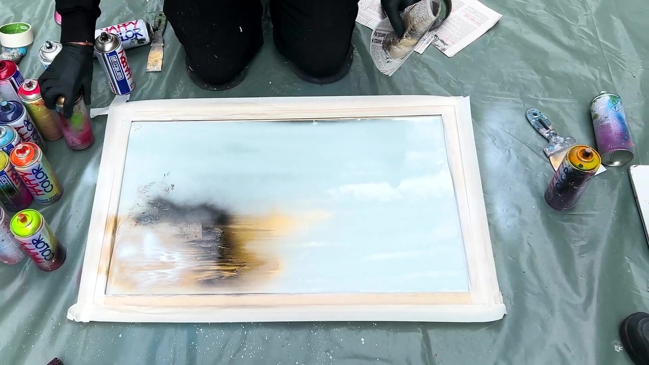 Street artist spray paints a tree on both sides of a mirror