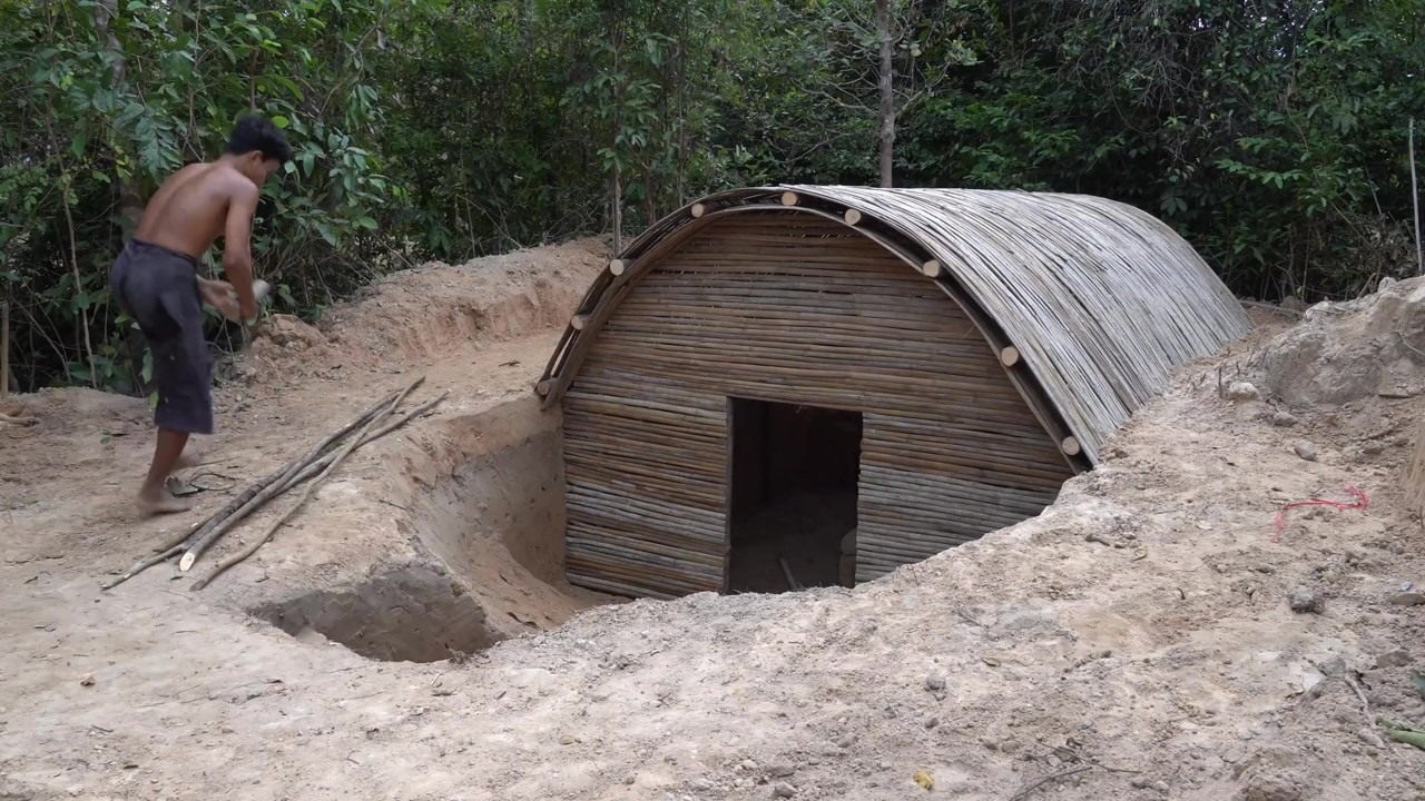 Green-roofed underground house with a curved stone entry