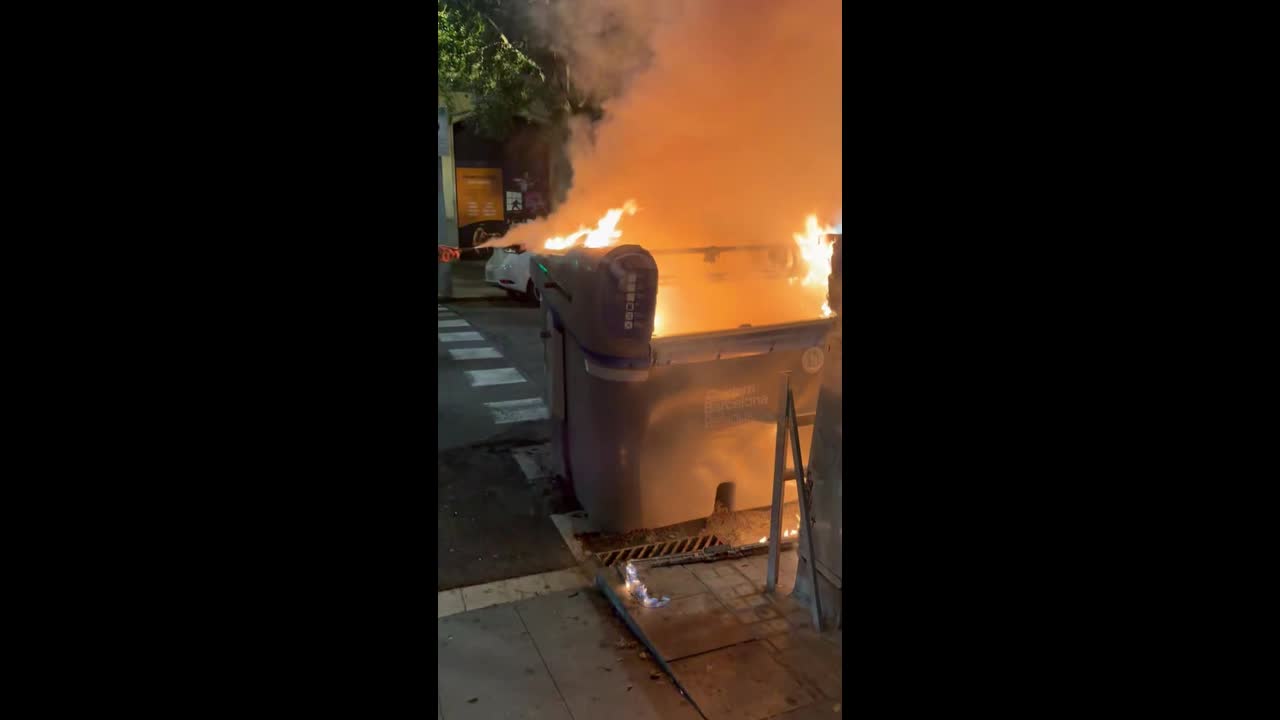 Man tries to extinguish burning rubbish bin amid unrest in Barcelona, Spain