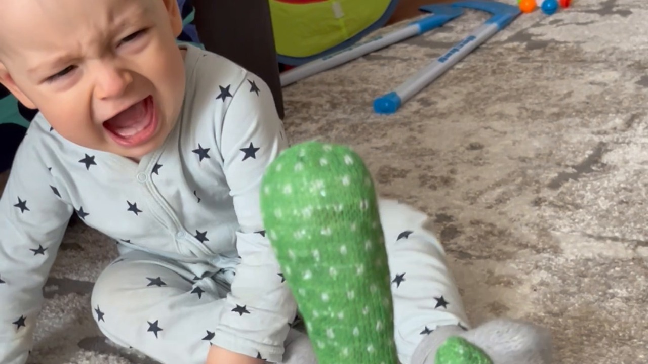 Baby scoots backward across rug after toy turns on
