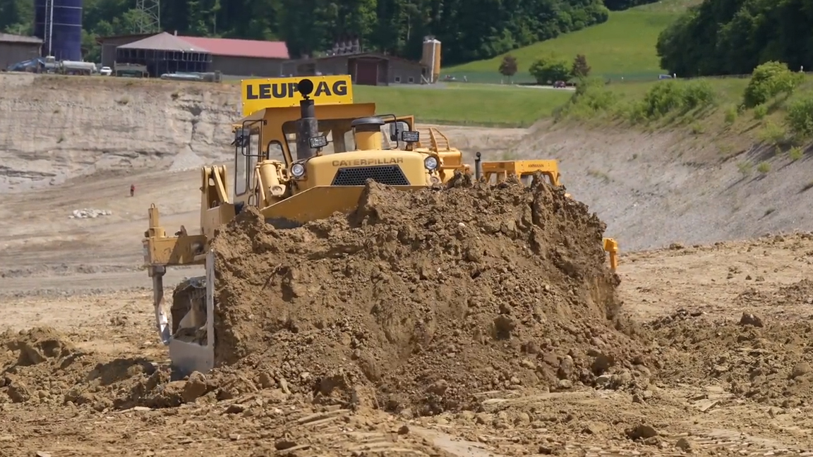 Massive bulldozer pushing a huge pile of dirt