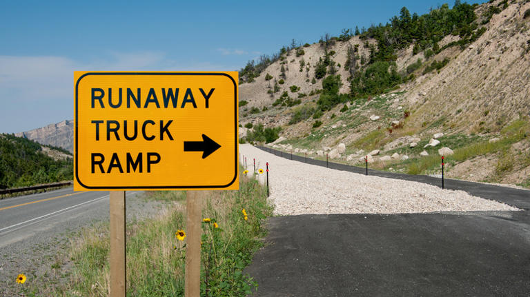 What does the percentage under a semi-truck symbol on a road sign mean?