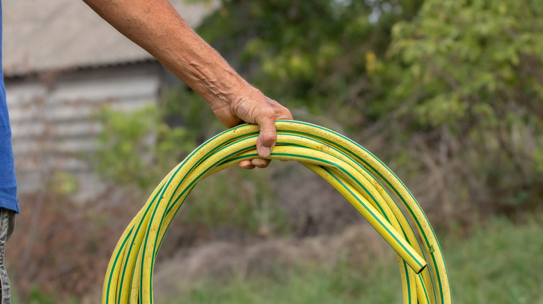 Use a wire hanger to keep garden hoses neat & organized