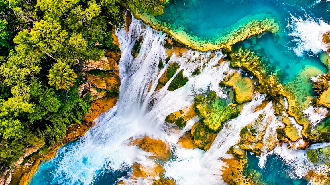Multiple waterfalls cascading over golden rocks into turquoise blue water