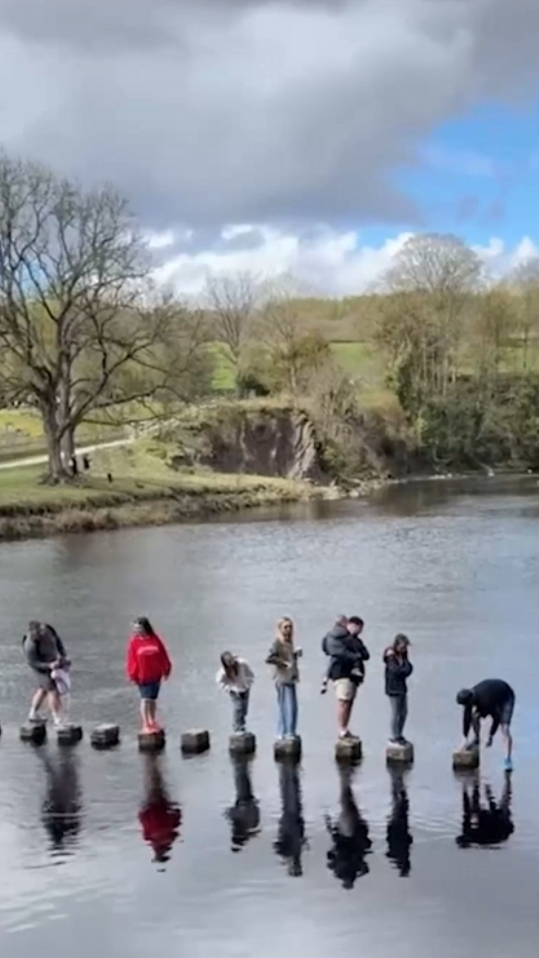 Father helps young daughter cross a stepping stone safely