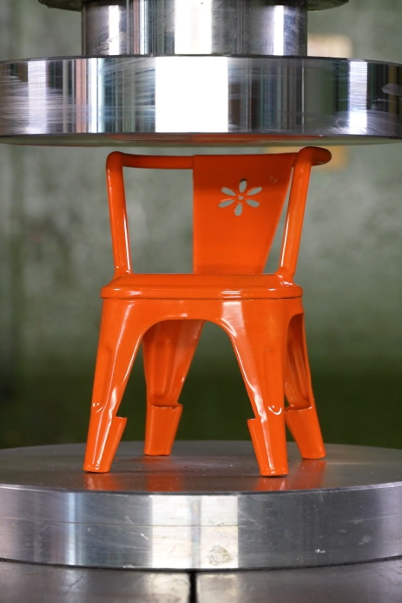 Hydraulic press vs small orange metal chair