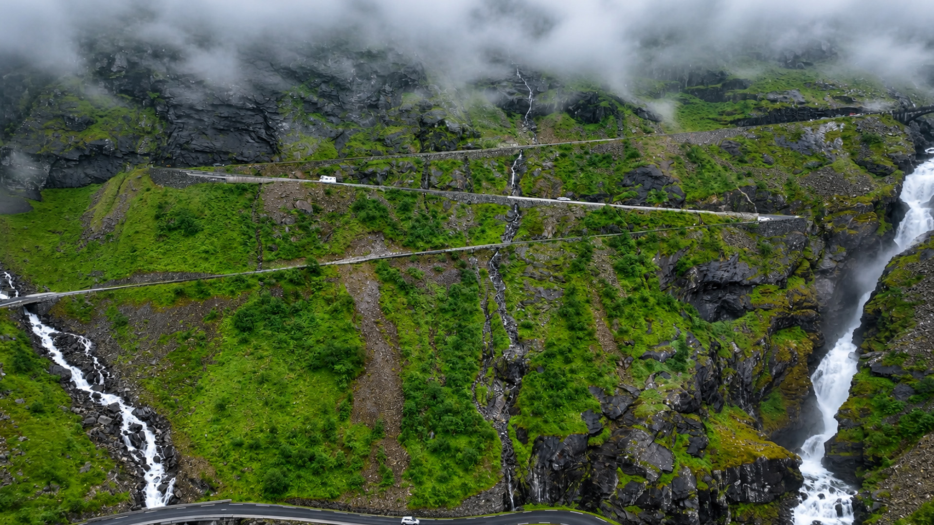 Winding roads climb a mountain covered in mist