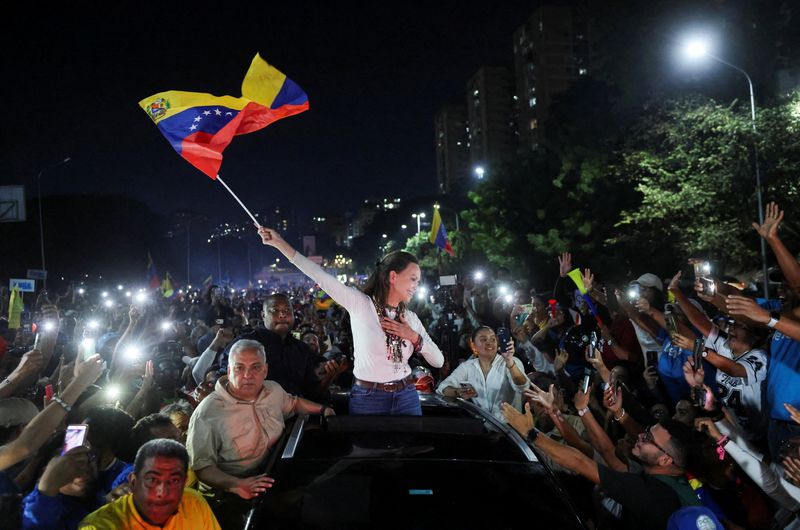 Venezuelan opposition leader Maria Corina Machado waves a Venezuela flag while greeting supporters as she arrives in Caracas after travelling by road from Barquisimeto, where she made her first public appearance following her return to the country after nearly a year abroad, in Caracas, Venezuela, October 25, 2026. REUTERS/Leonardo Fernandez Viloria