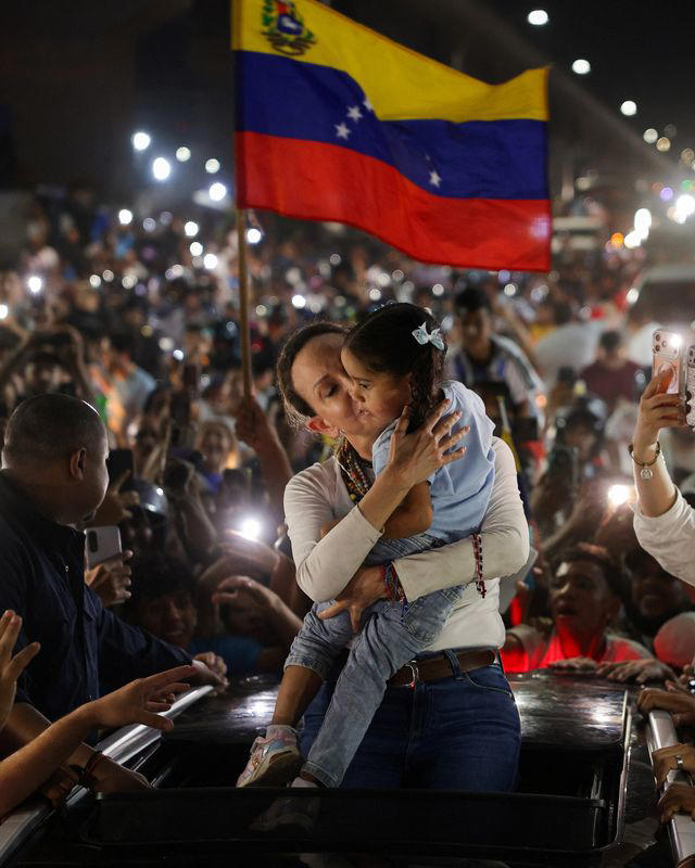 Venezuelan opposition leader Maria Corina Machado carries a girl as she greets supporters along a highway after returning to Venezuela following nearly a year abroad, in Maracay, Venezuela, October 25, 2026. REUTERS/Gaby Oraa