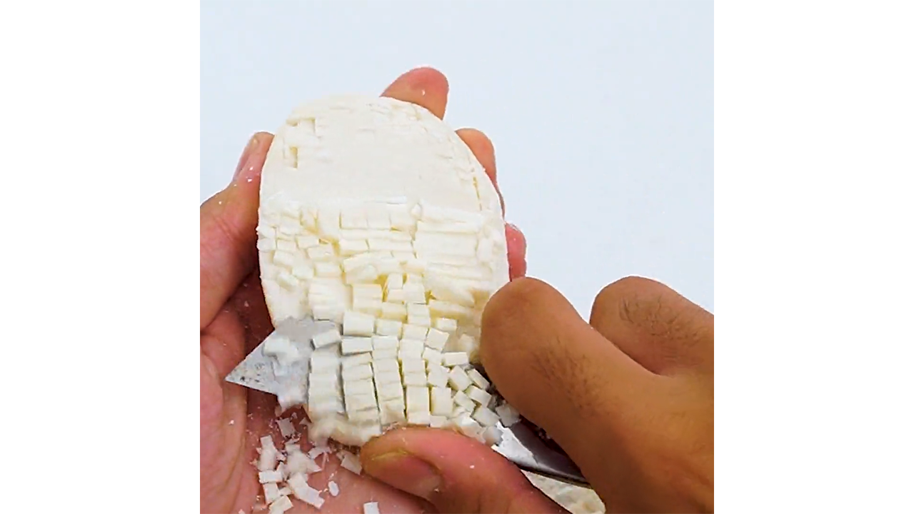 Scraping white soap into thick rectangular chips